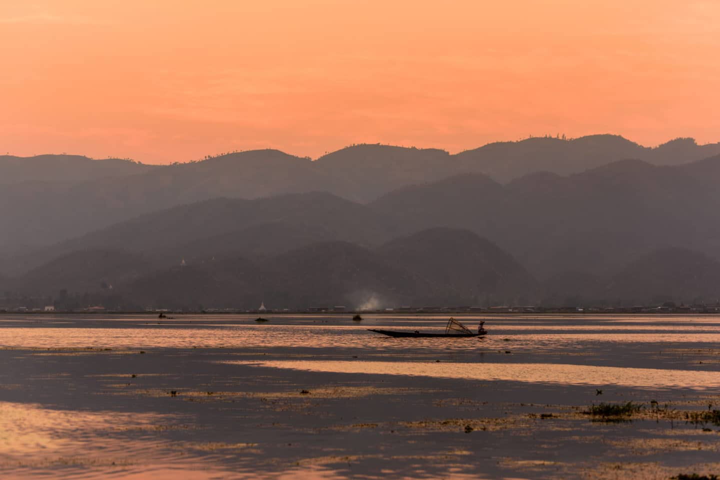 fishing boat in lake with mountain background