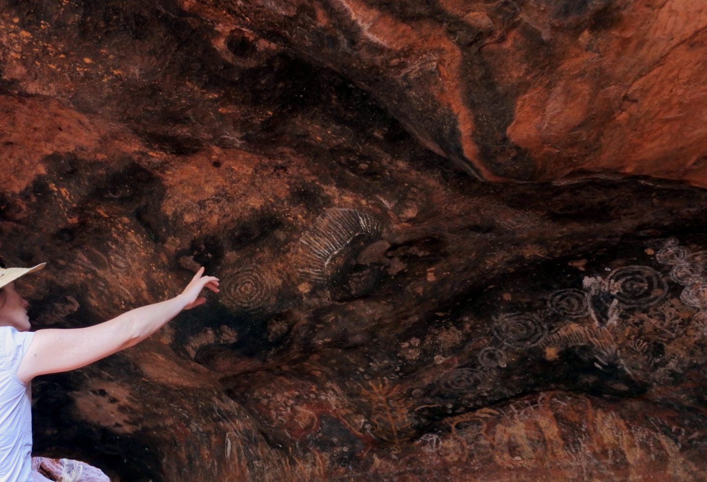 Woman looking at cave painting in Uluru.