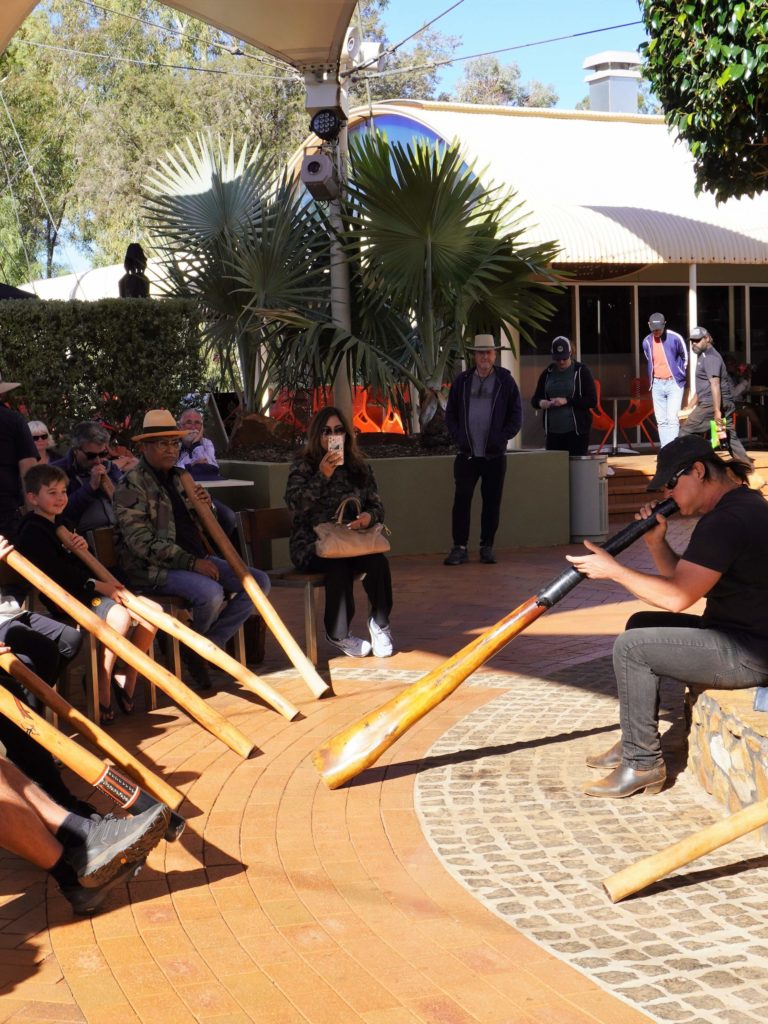 A group of people playing didgeridoos in an outdoor setting.