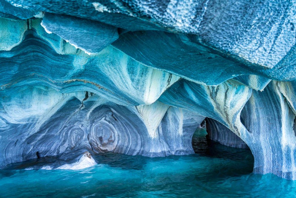 A stunning view of the inside of a cave, with elaborate patterns and layers of blue and white on the walls.