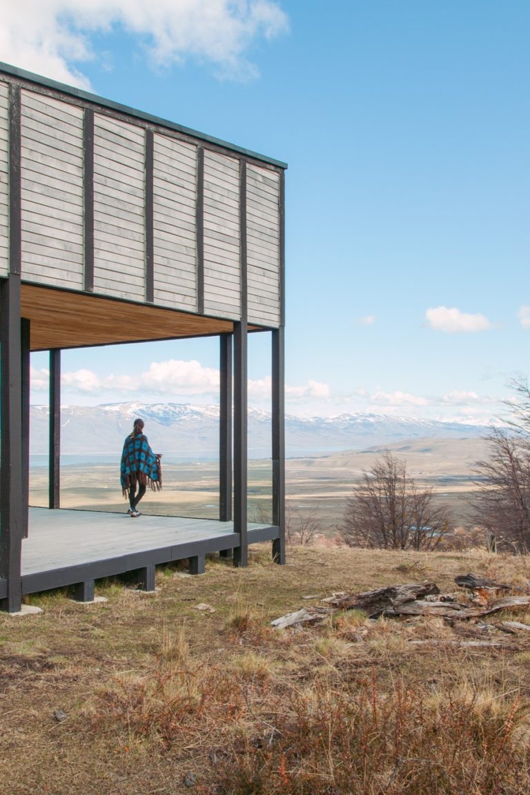 A charming cabin with an appealing veranda against the backdrop of a breathtaking panoramic view of majestic mountains in the distance.
