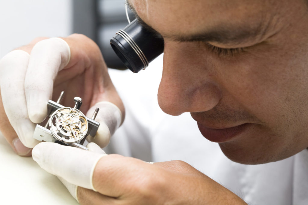 A watchmaker meticulously repairs mechanical watches in his workshop, showcasing precision and craftsmanship.