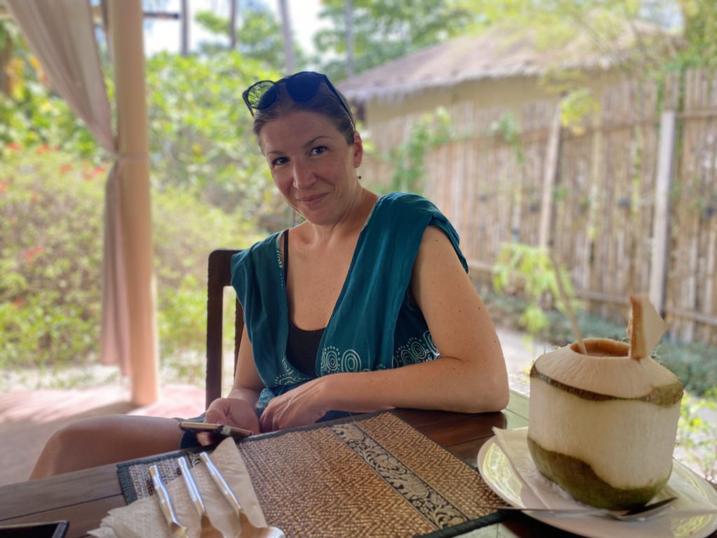 Korine Weideli sits ata table with a coconut drink