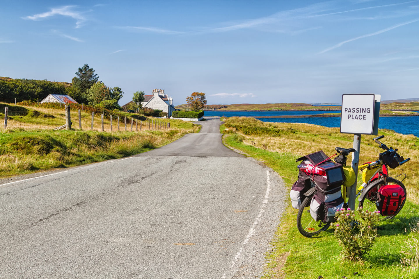 A cyclist riding on a scenic countryside trail, surrounded by panoramic views of the rural landscape, with pannier bags on the bike.