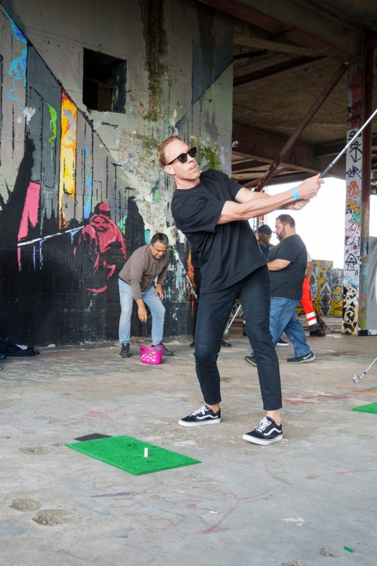 A man swings a golf club on the roof of a location during an event in Berlin.