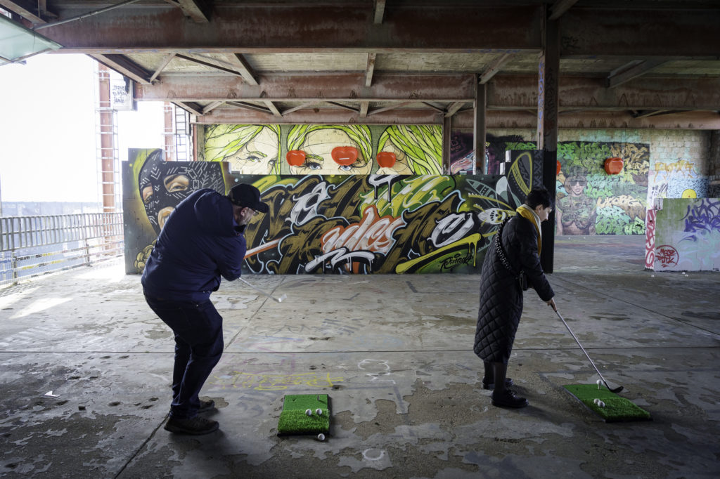 Two participants of an event in Berlin play golf on the roof of a location.
