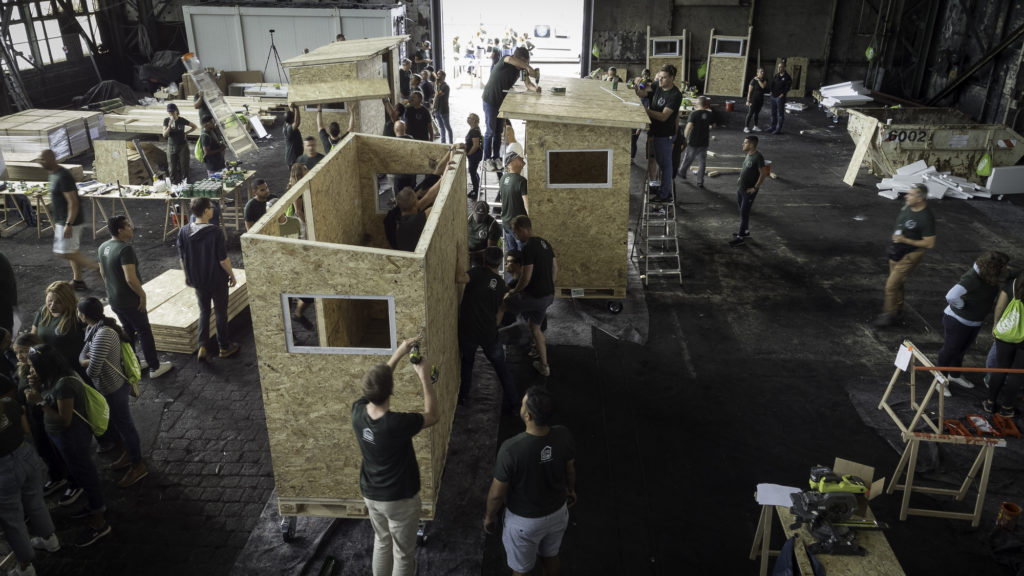Volunteers work together to build houses for the homeless as part of a CSR project during an event in Berlin.