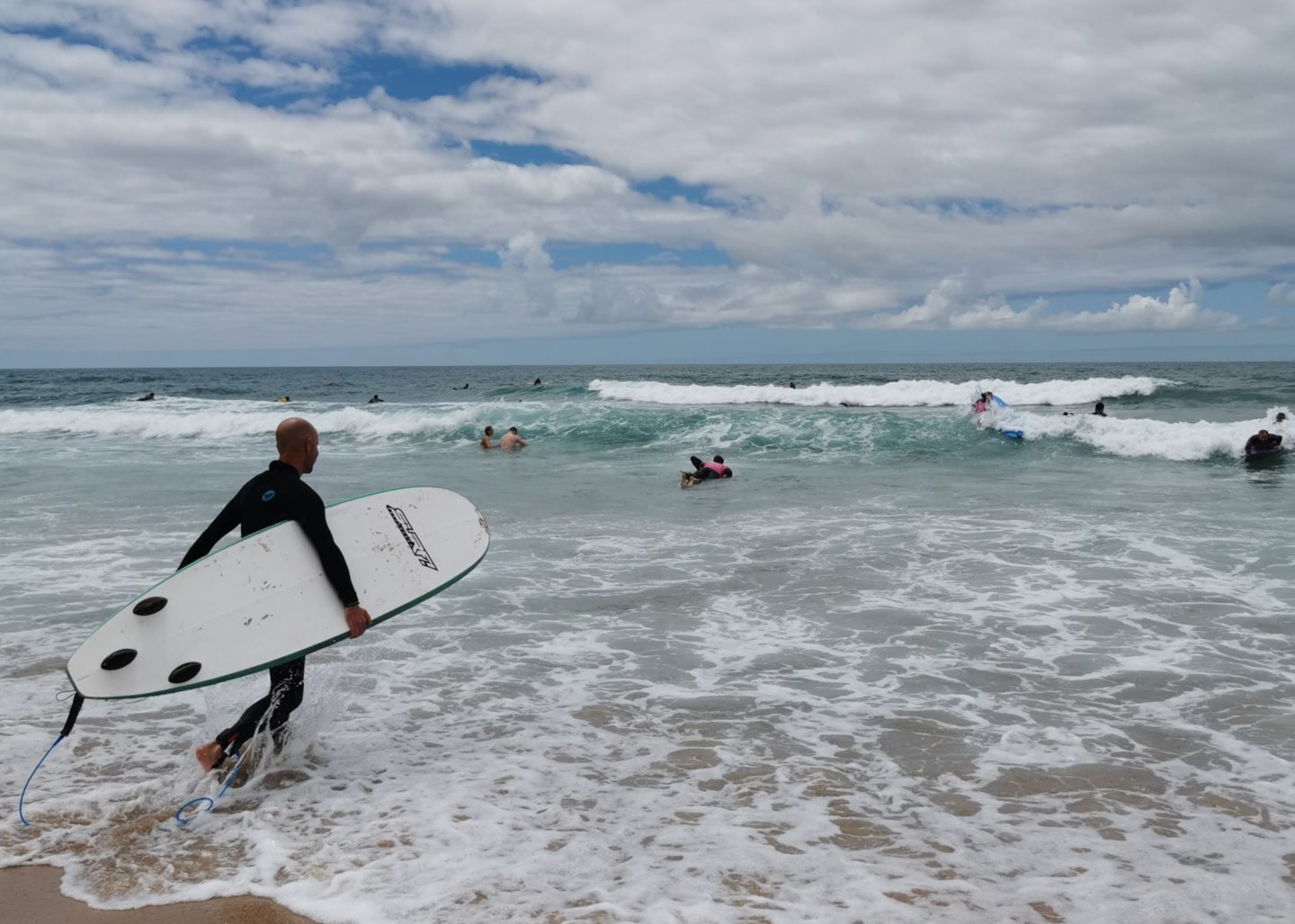 A guest ventures into the sea with his surfboard during an event in Portugal.