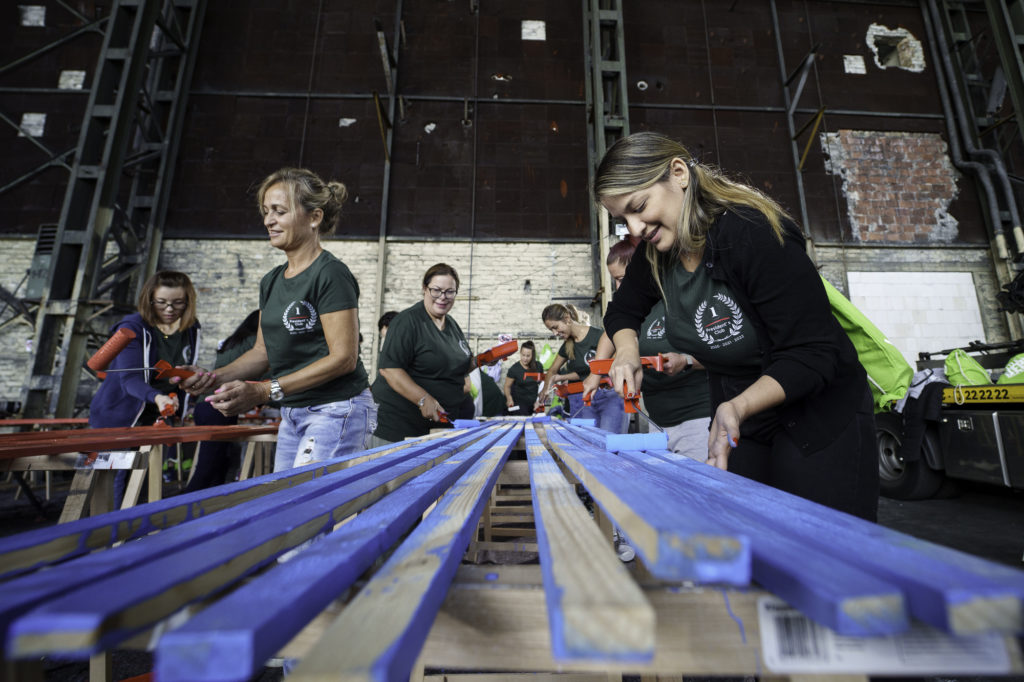A woman paints wood blue during a CSR project in Berlin.