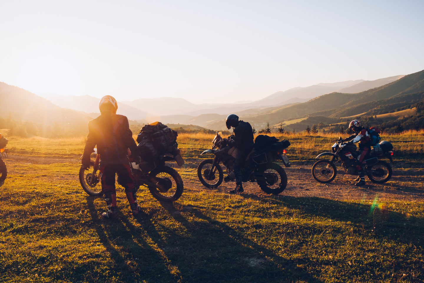 A group of motorcyclists make a stop during the sunset.