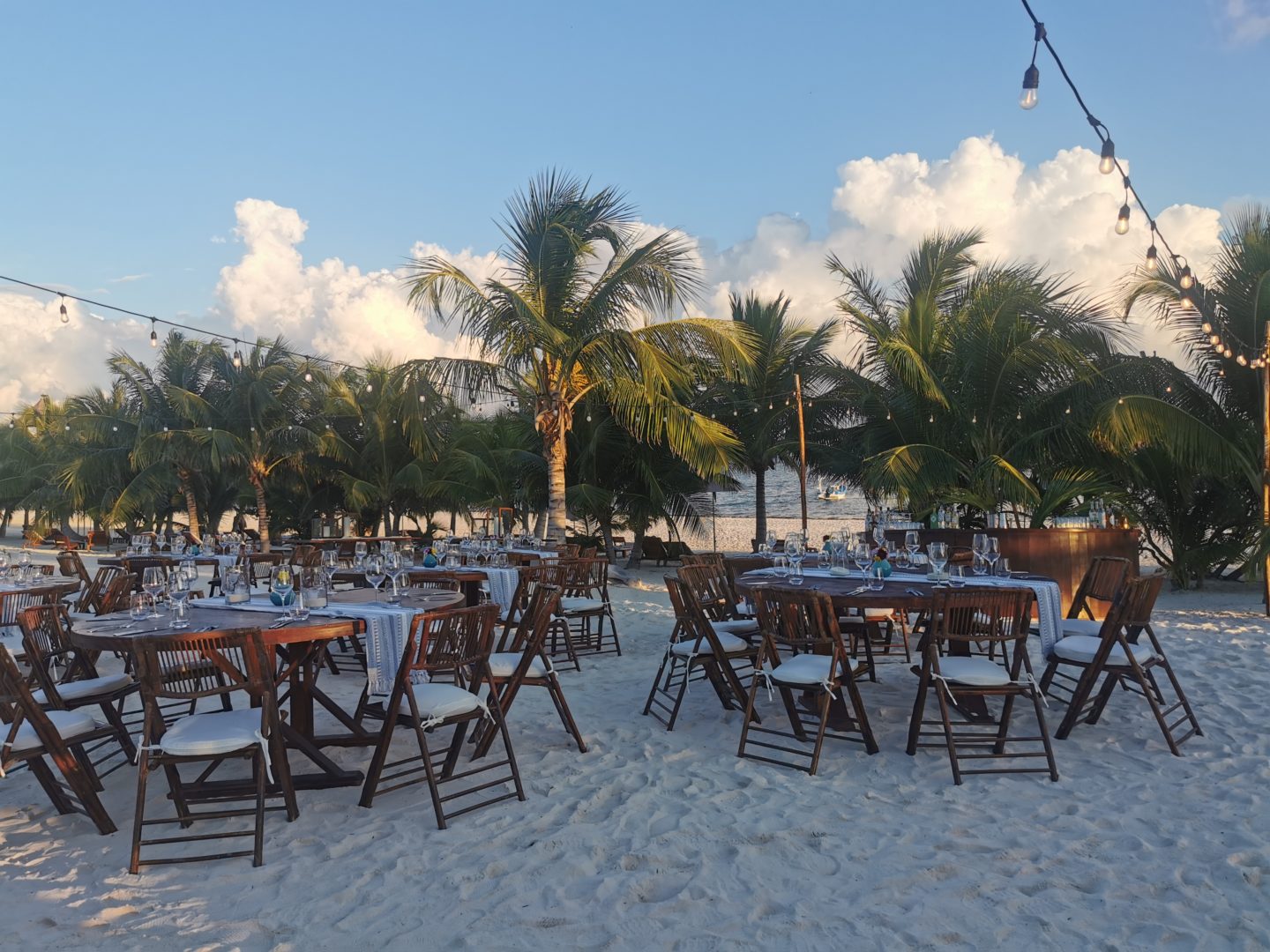 Tables are set on the sand with a view of the sea during an event in Mexico.
