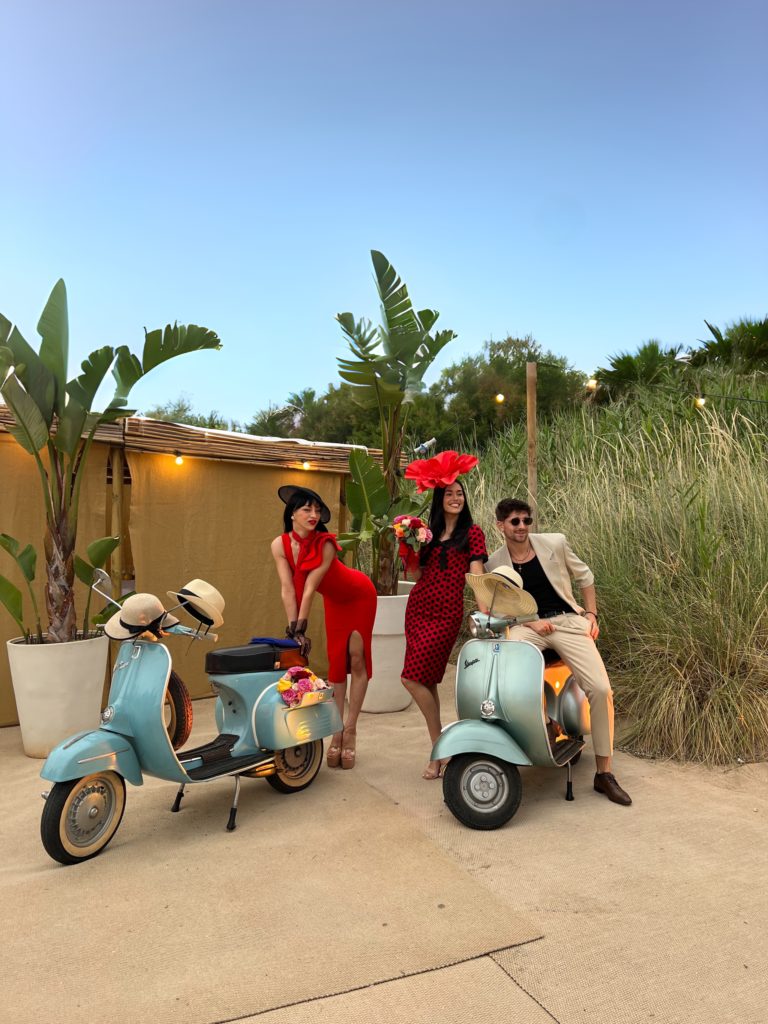 Three models pose in front of two vespas during a private event in Puglia, Italy.