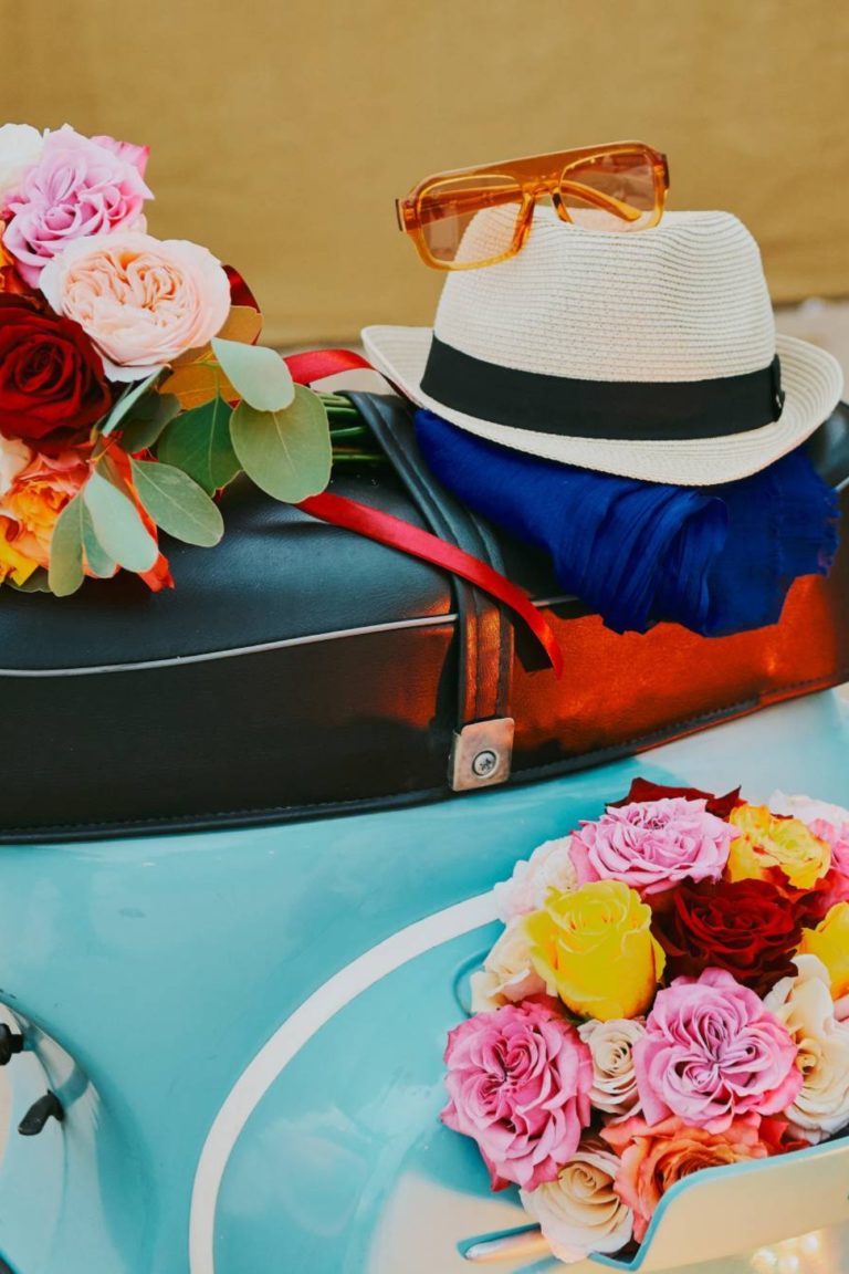 The vespa features decorations such as a hat, sunglasses and flowers.