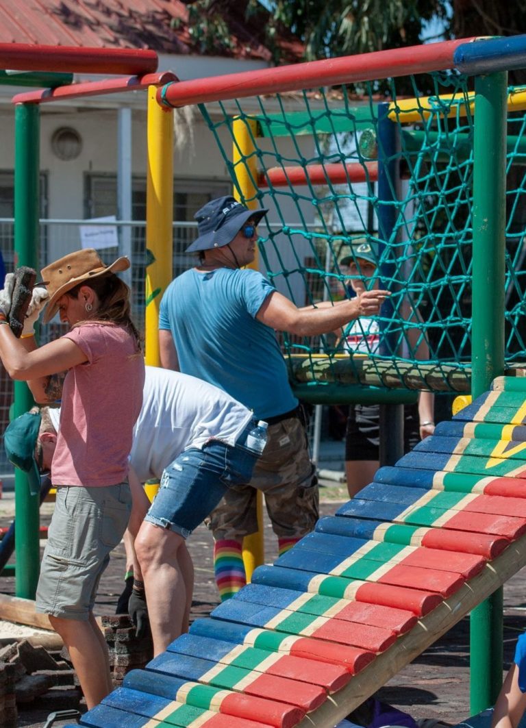 A group of people builds a colourful playground for the children of a primary school.